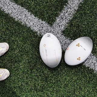 Förderung von Sportplatzbewässerung: Zwei Rugbybälle auf Kunstrasen an einer Spielfeldlinie als Motiv für professionelle Sportplatzbewässerung in modernen Sportanlagen