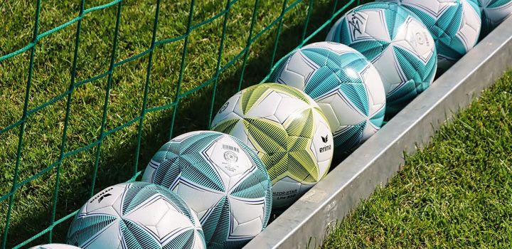 Förderung von Sportplatzbewässerung: Fußbälle am Spielfeldrand auf dichtem Rasen passend für Sportplatzbewässerung und moderne Sportanlagen