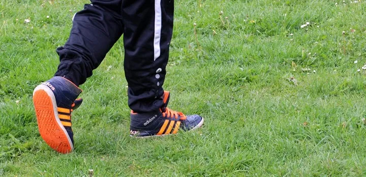 Beine mit Sportschuhen auf einem stark beanspruchten Sportrasen mit guter Sportplatzbewässerung